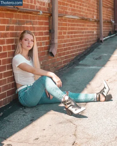 Marris Gulledge - girl sitting against a brick wall with her legs crossed