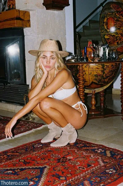 maya.keyy - woman in a white bikini and hat crouching on a rug