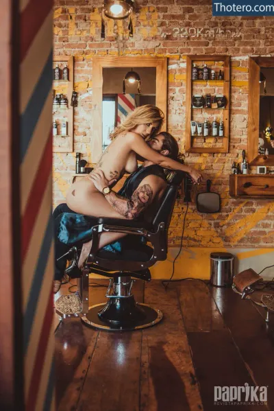 Fabi Guedes - woman sitting in a barber chair while a man shaves his hair