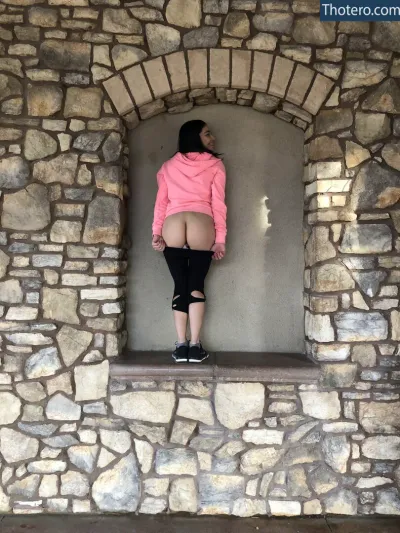 emilywillisxxx - woman in pink jacket standing on ledge in stone wall