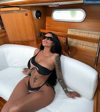 Enise Sude - woman in black bikini sitting on a white couch in a boat