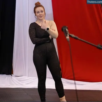 Beth Roars - woman in black jumpsuit standing on stage with microphone