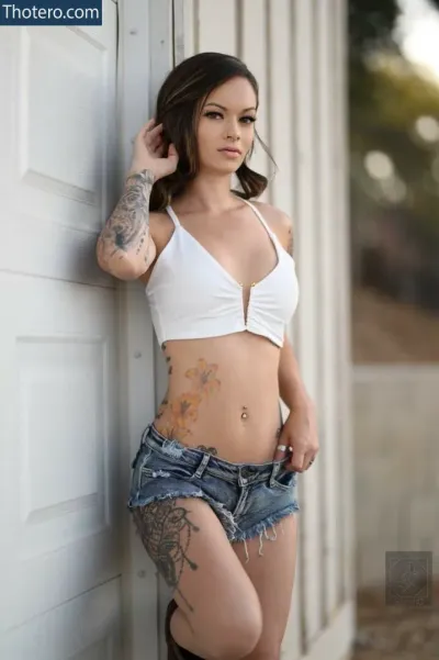 Tkillaaa_xxoo - a woman with tattoos leaning against a wall with her hand on her hip