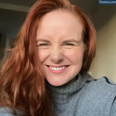 Beth Roars - smiling woman with red hair and a blue turtle neck sweater