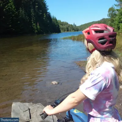 Aurora Indica - woman riding a bike on a river bank with a helmet on