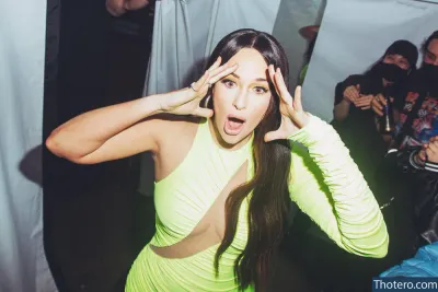 Kacey Musgraves - woman in a yellow dress making a face with her hands
